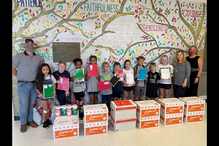 Kids and staff stand in front of boxes of school supplies